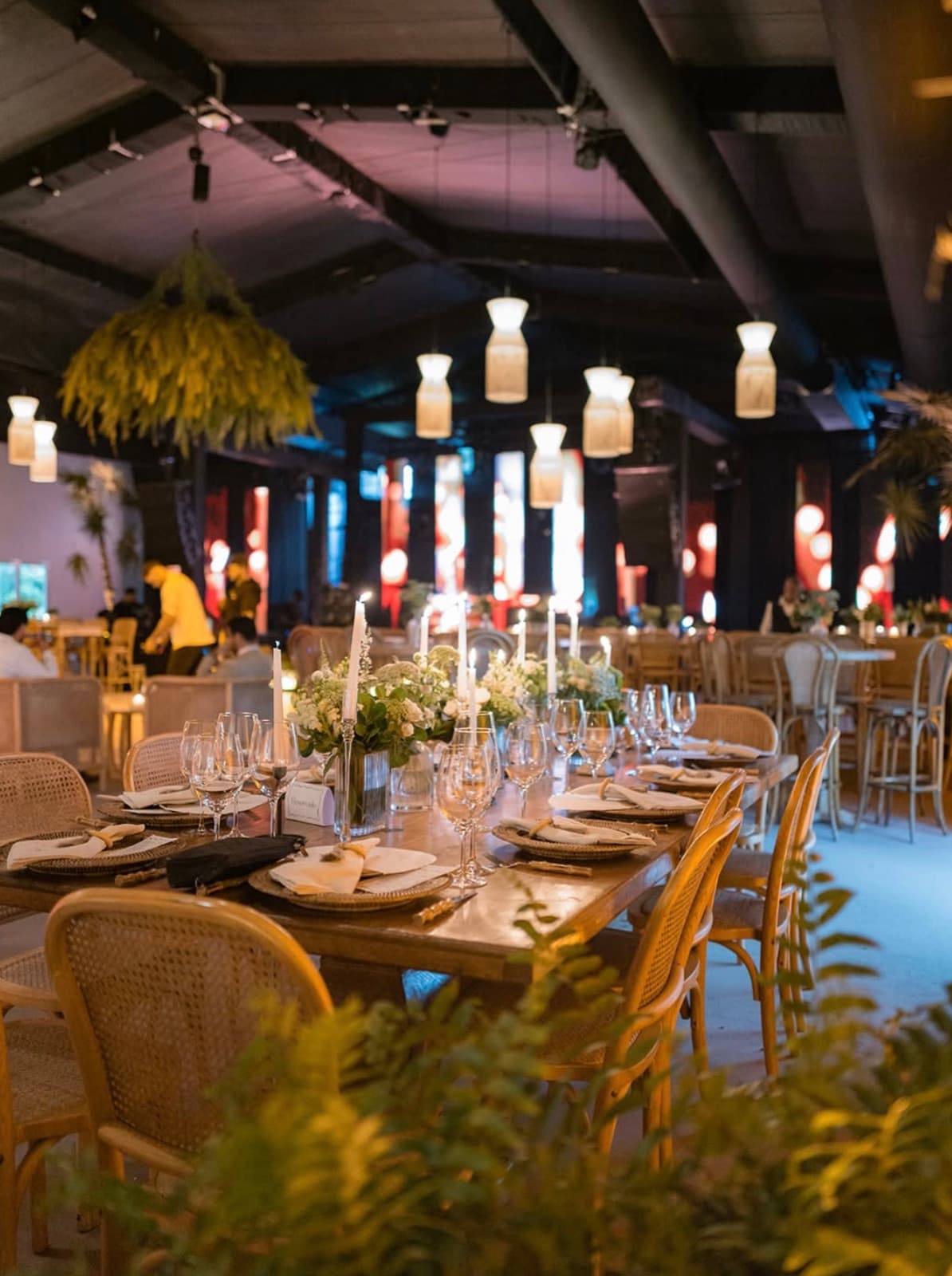 Mesa larga decorada con velas, flores y lámparas colgantes en CasaPalmera Tent