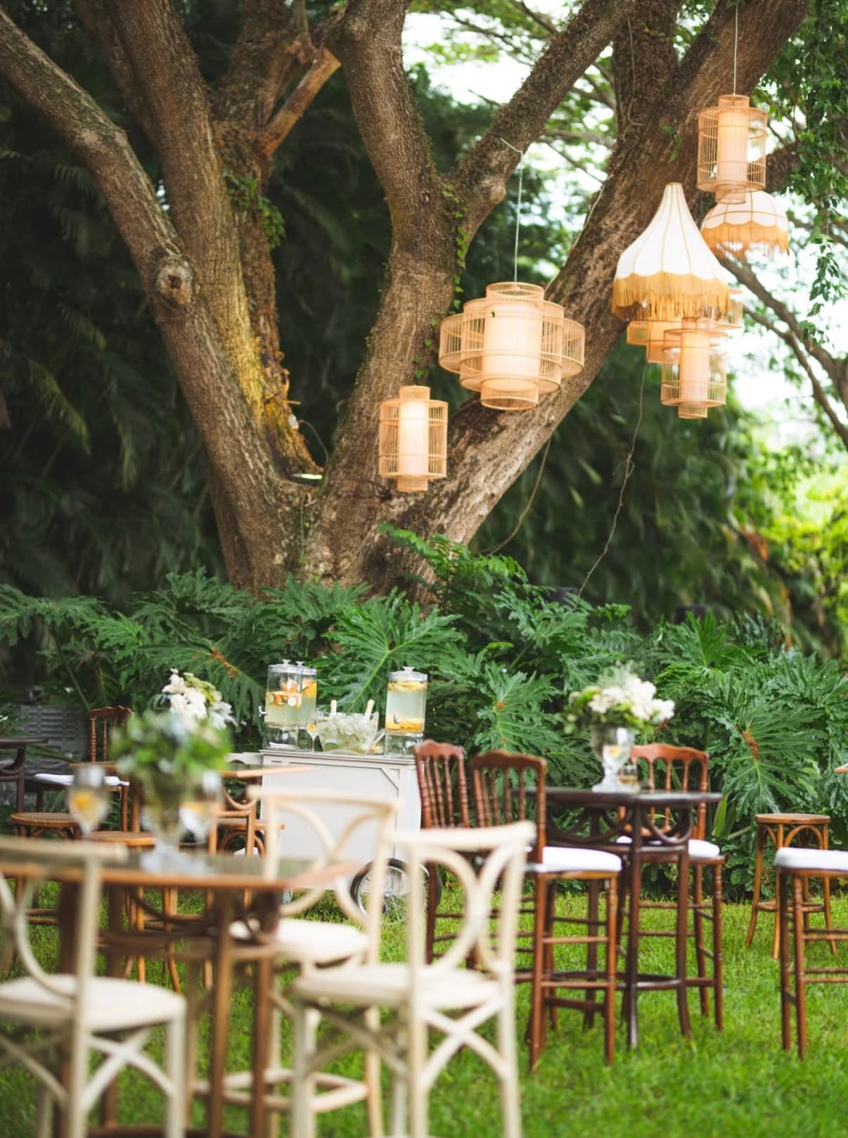 Montaje de cocktail en jardín con lámparas colgantes y mobiliario lounge