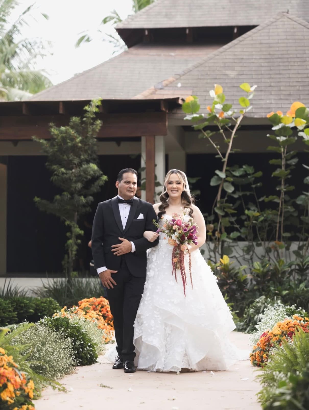 Novia entrando por el jardín de CasaPalmera Tent con flores tropicales